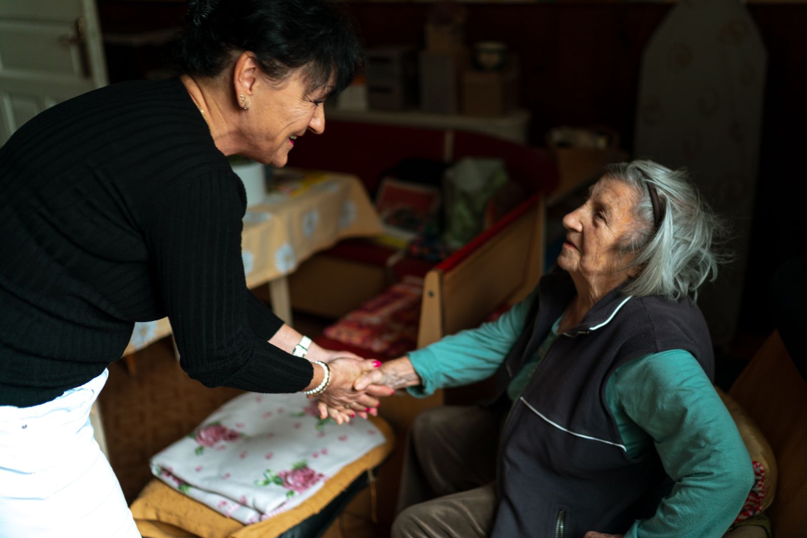 A carer taking an older woman’s hands as she arrives